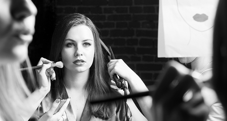 A model having her makeup applied and hair styled looking in the mirror 1 