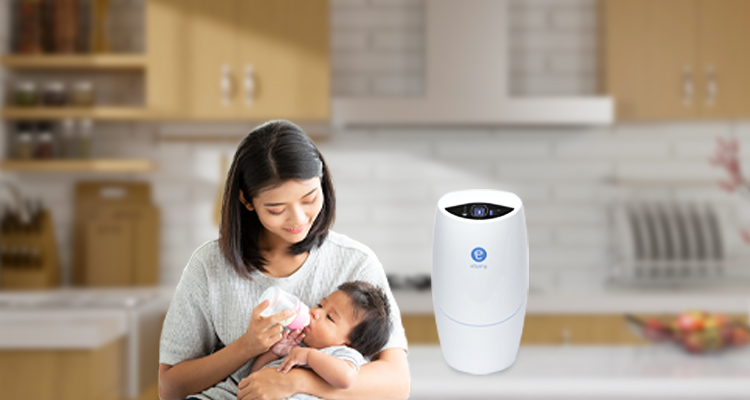 A mother feeding her baby next to an eSpring Water Treatment System unit 