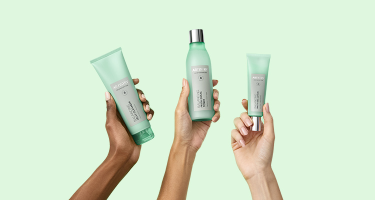 Three hands holding up ARTISTRY SKIN NUTRITION Balancing Solution products against a green background 